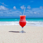 foto de um drink no chão na areia da praia